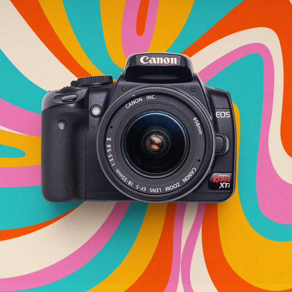 Front view of a restored Canon Rebel XTi DSLR camera with an 18–55mm lens on a colorful retro background