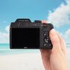 Back view of the Nikon COOLPIX B500 showing its LCD screen and controls against a beach backdrop