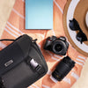 Nikon D3100 dual-lens kit styled with a camera bag and colorful summer accessories