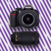 Nikon D3100 DSLR with a standard lens and telephoto zoom lens on a purple striped background