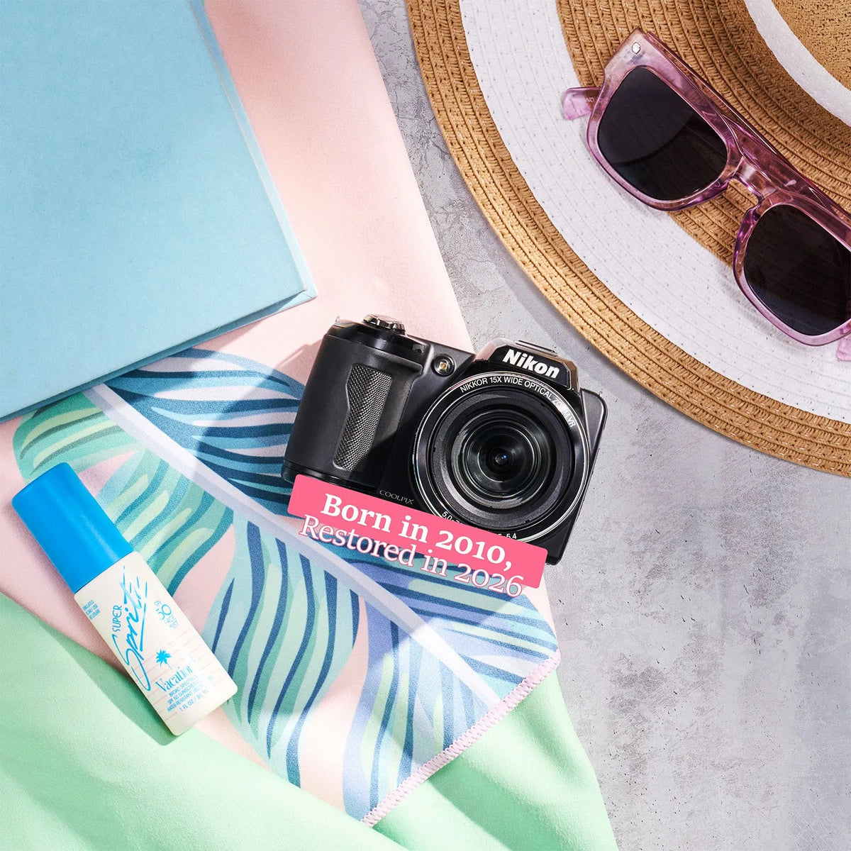 Restored Nikon COOLPIX L110 styled with summer accessories and text reading “Born in 2010, Restored in 2026”