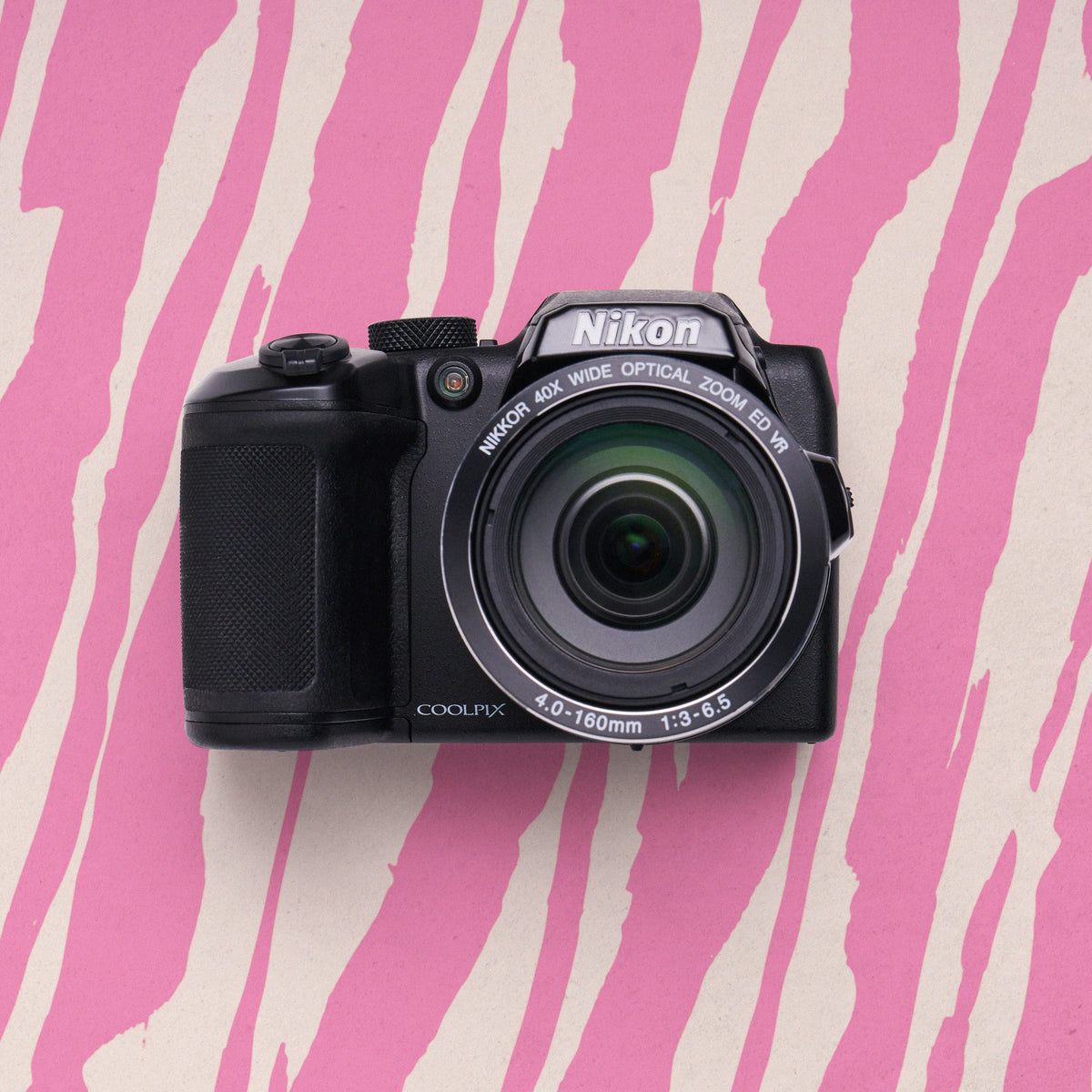 Front view of a black Nikon COOLPIX P510 superzoom camera on a pink zebra-patterned background