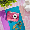 Restored purple Nikon Coolpix S4100 styled with jewelry and text reading “Born in 2011, Restored in 2026”