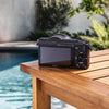 Back view of the Sony a5100 showing its LCD screen and controls beside a swimming pool