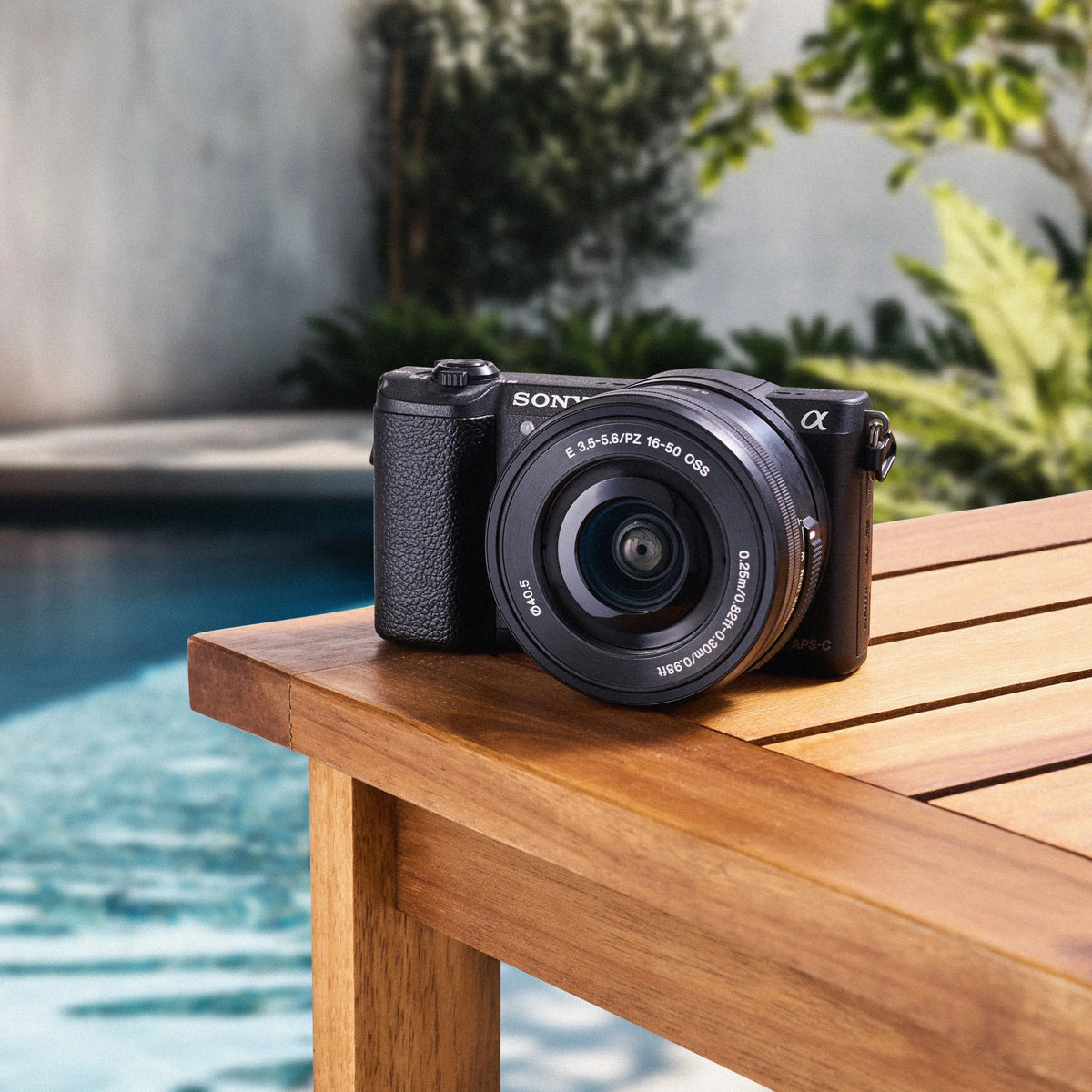 Sony a5100 mirrorless camera with a 16–50mm lens displayed beside a swimming pool