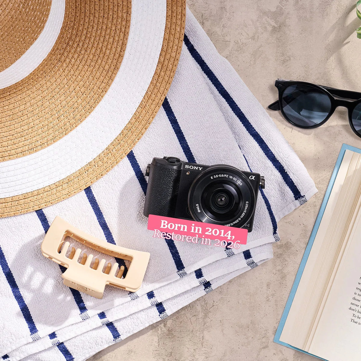Restored Sony a5100 styled with a sun hat and sunglasses, labeled Born in 2014, Restored in 2026