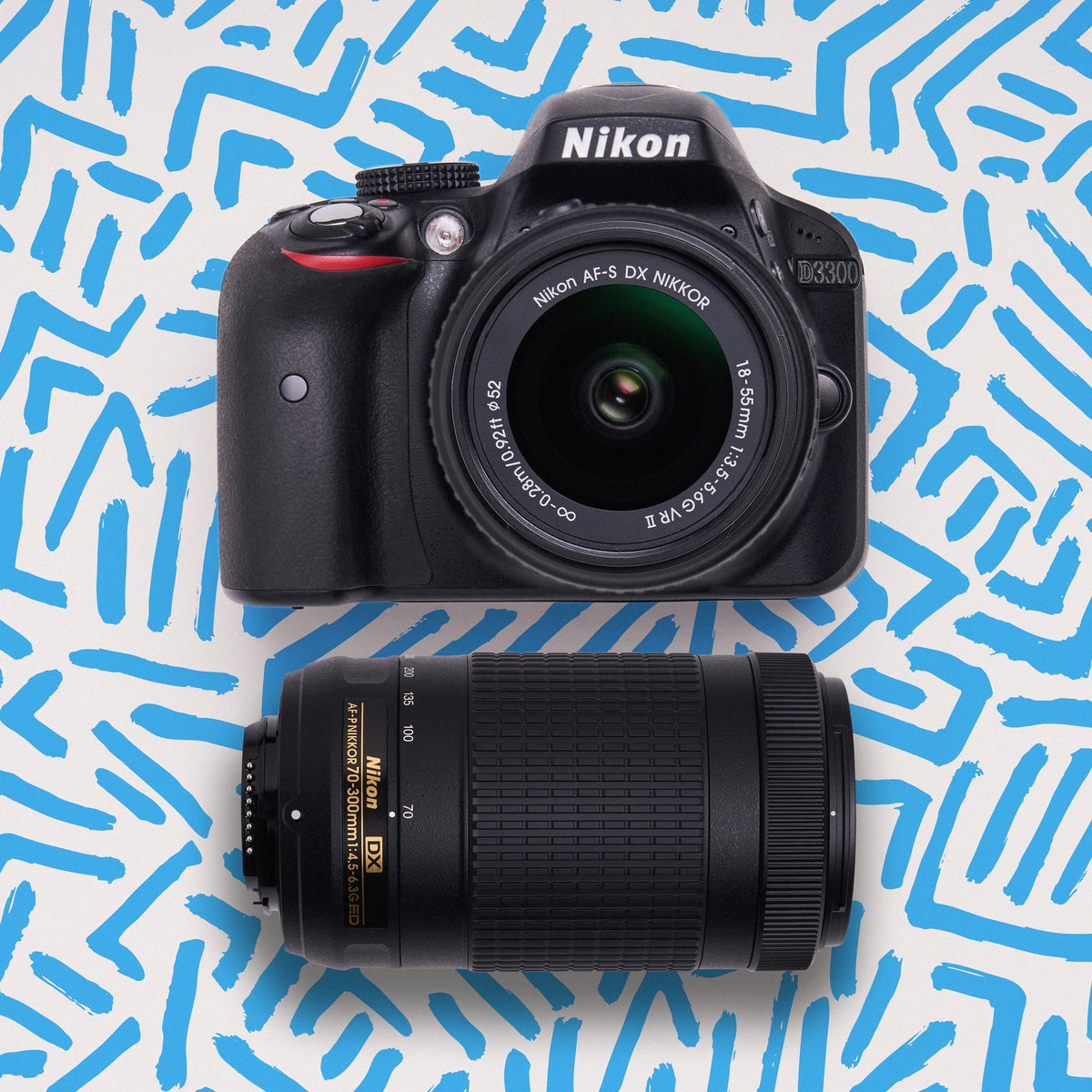 Nikon D3300 DSLR camera with 18–55mm and 70–300mm lenses on a blue patterned background