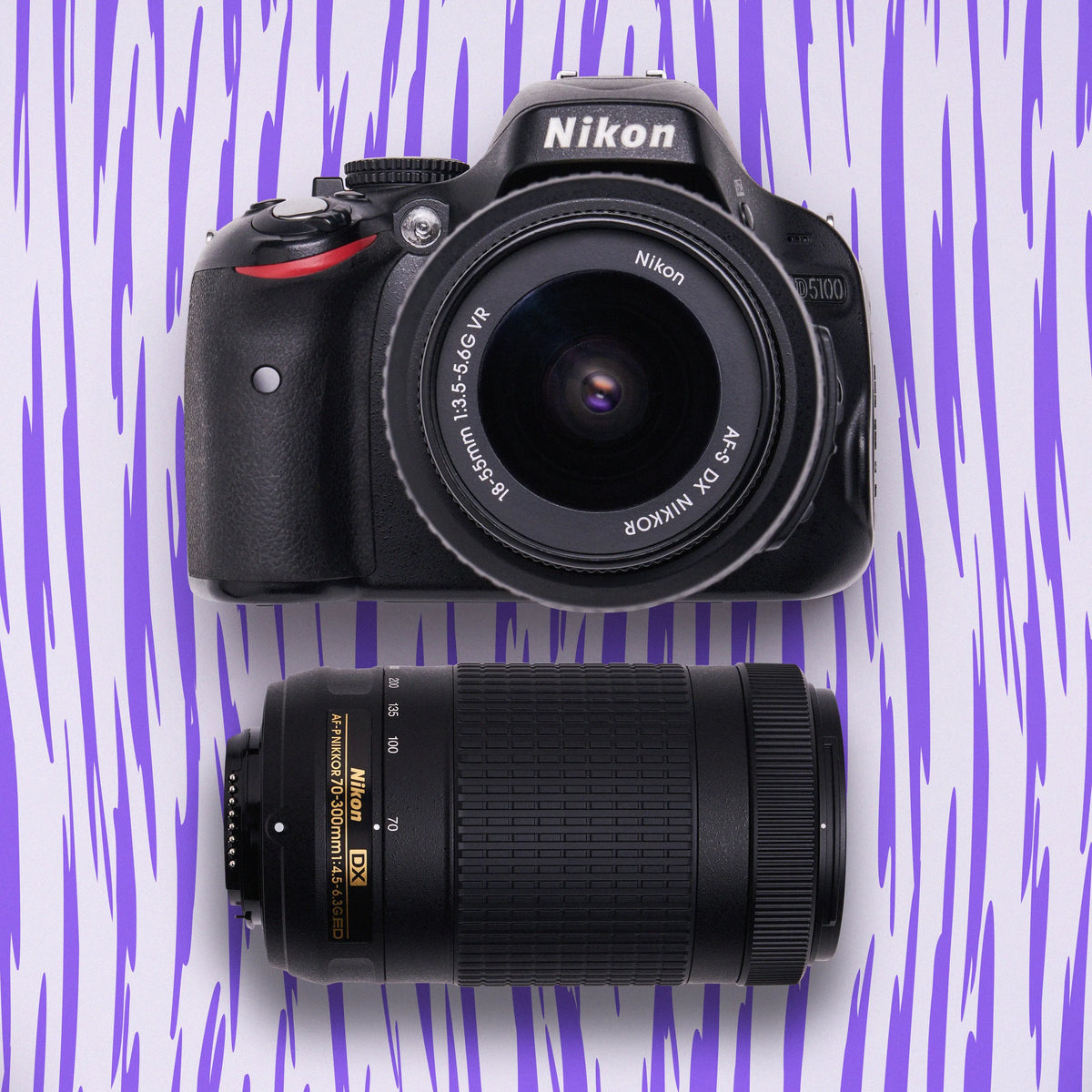 Nikon D5100 DSLR camera with 18–55mm and 55–200mm lenses on a purple patterned background