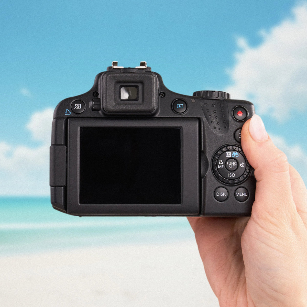 Back view of a black Canon PowerShot SX50 HS showing its LCD screen and controls at the beach