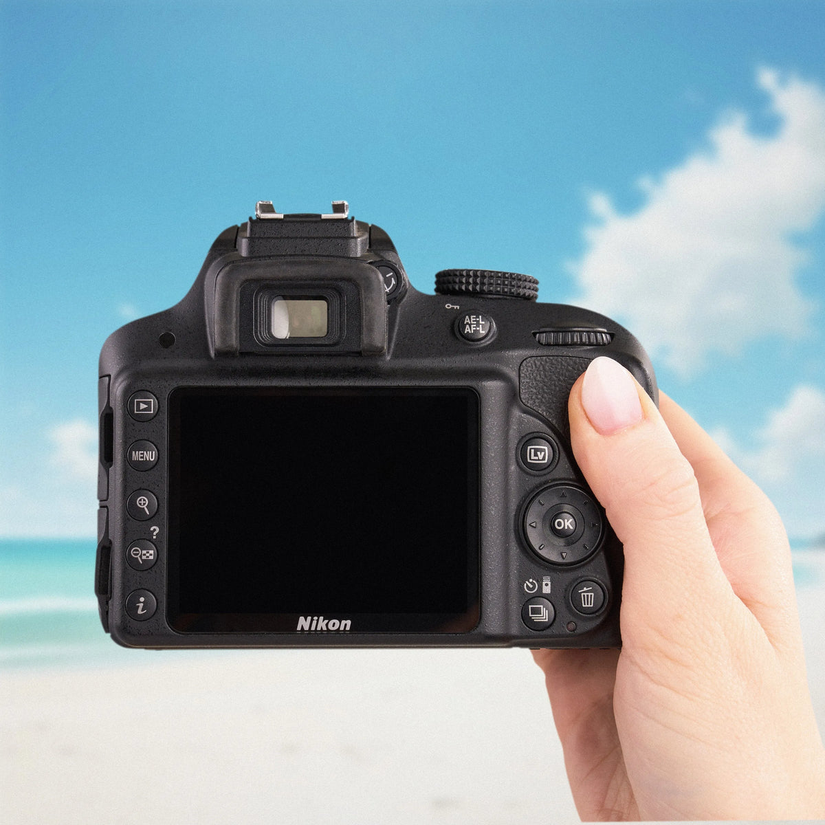 Back view of a Nikon D3300 DSLR showing its LCD screen and controls against a beach background