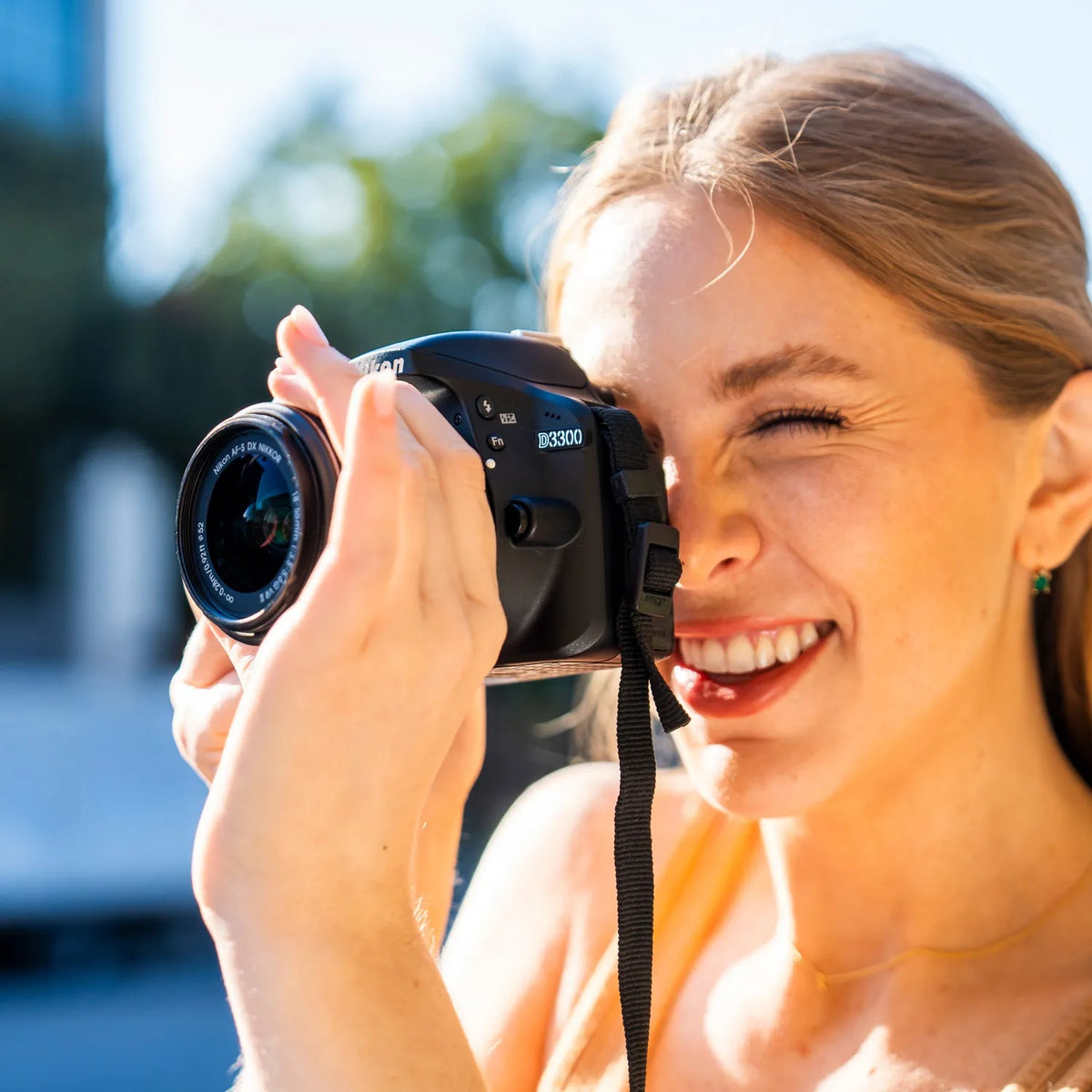 Woman taking a photo with a Nikon D3300 beginner DSLR camera outdoors