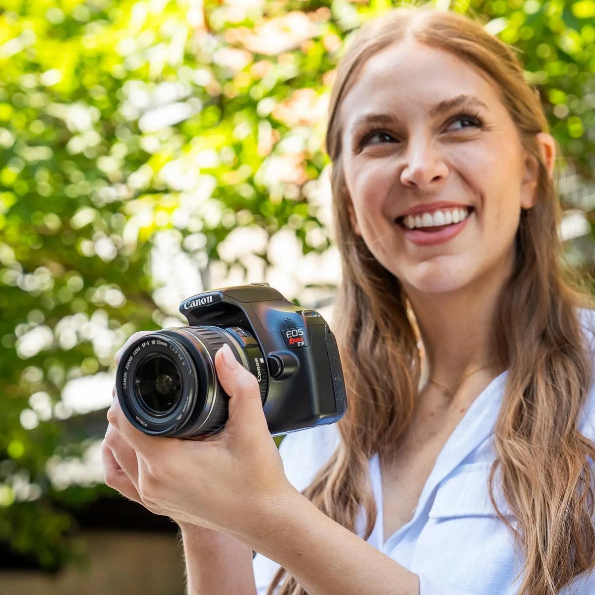 Woman holding a Canon Rebel T3 DSLR camera outdoors