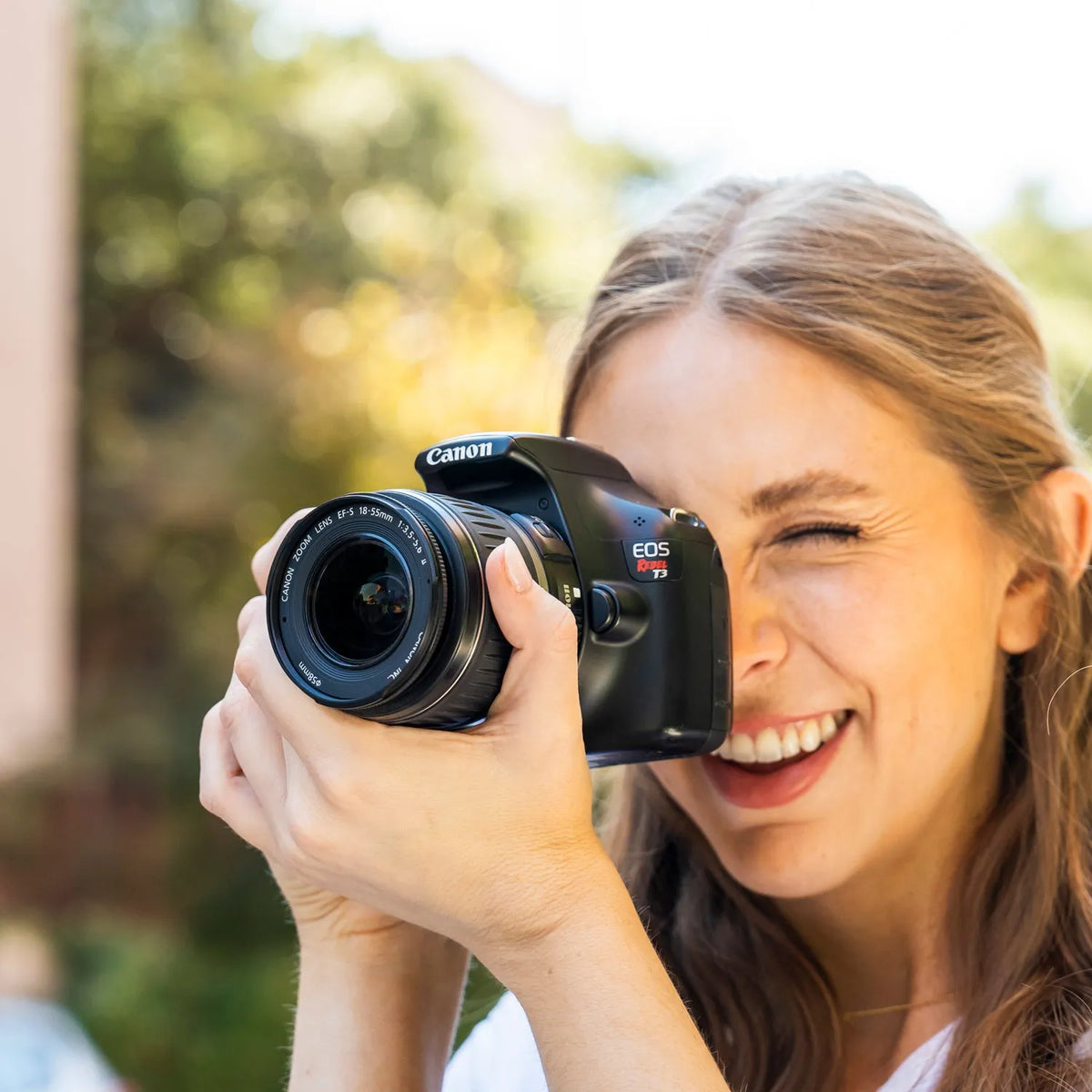 Woman taking a photograph outdoors with a Canon Rebel T3 DSLR camera