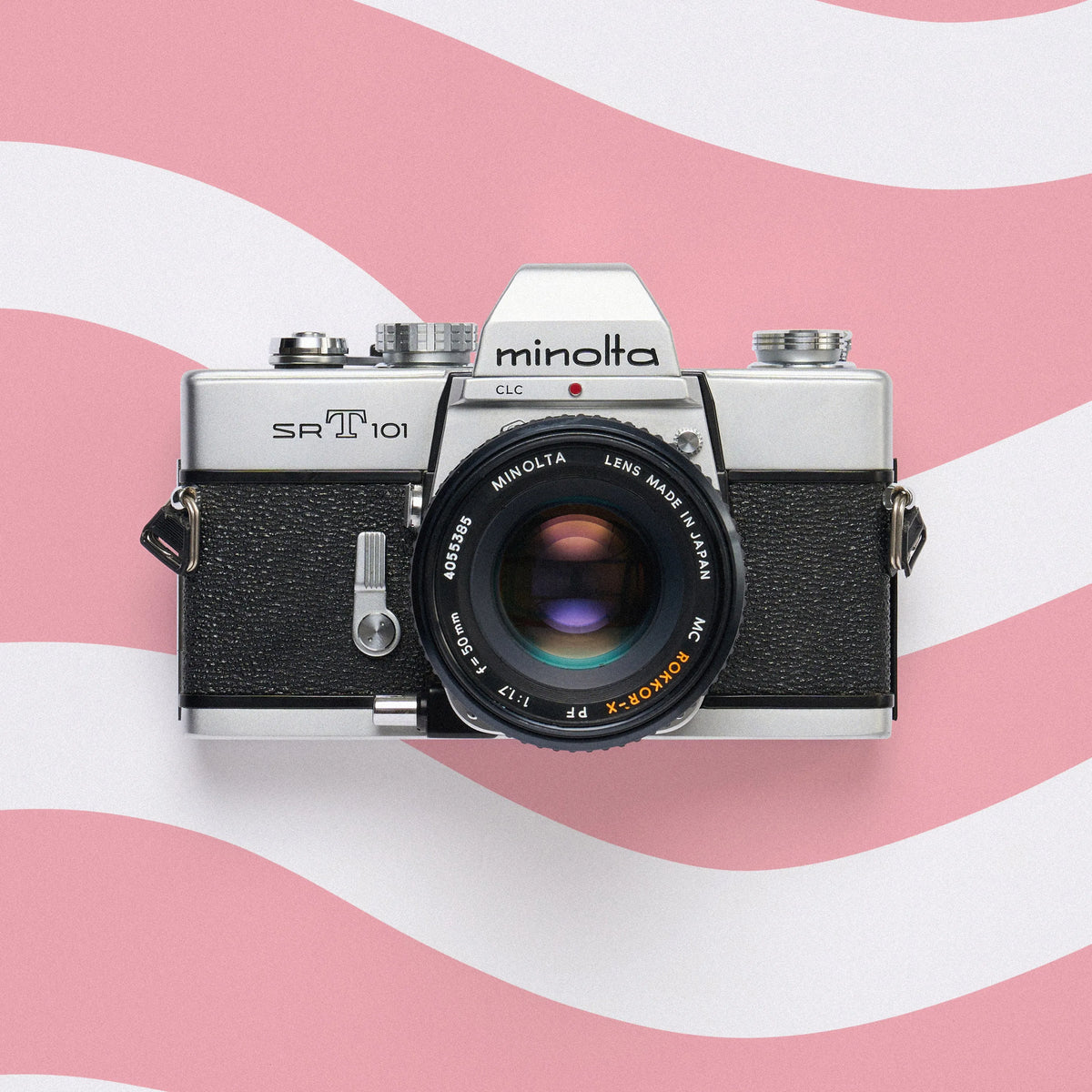 Minolta SRT 101 35mm film camera on a pink and white wavy background