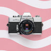 Minolta SRT 101 35mm film camera on a pink and white wavy background