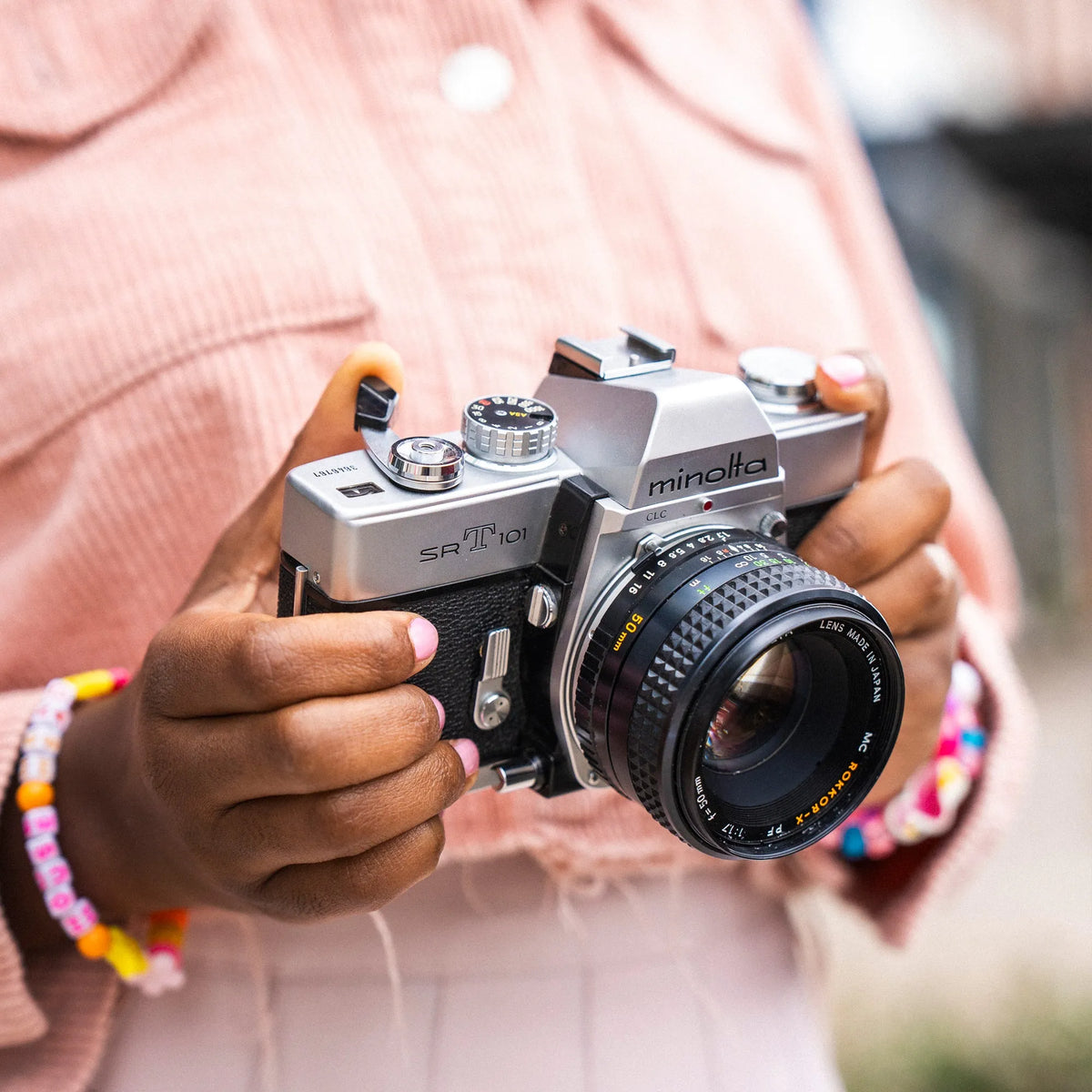 Person holding a Minolta SRT 101 35mm film camera with a blurred background