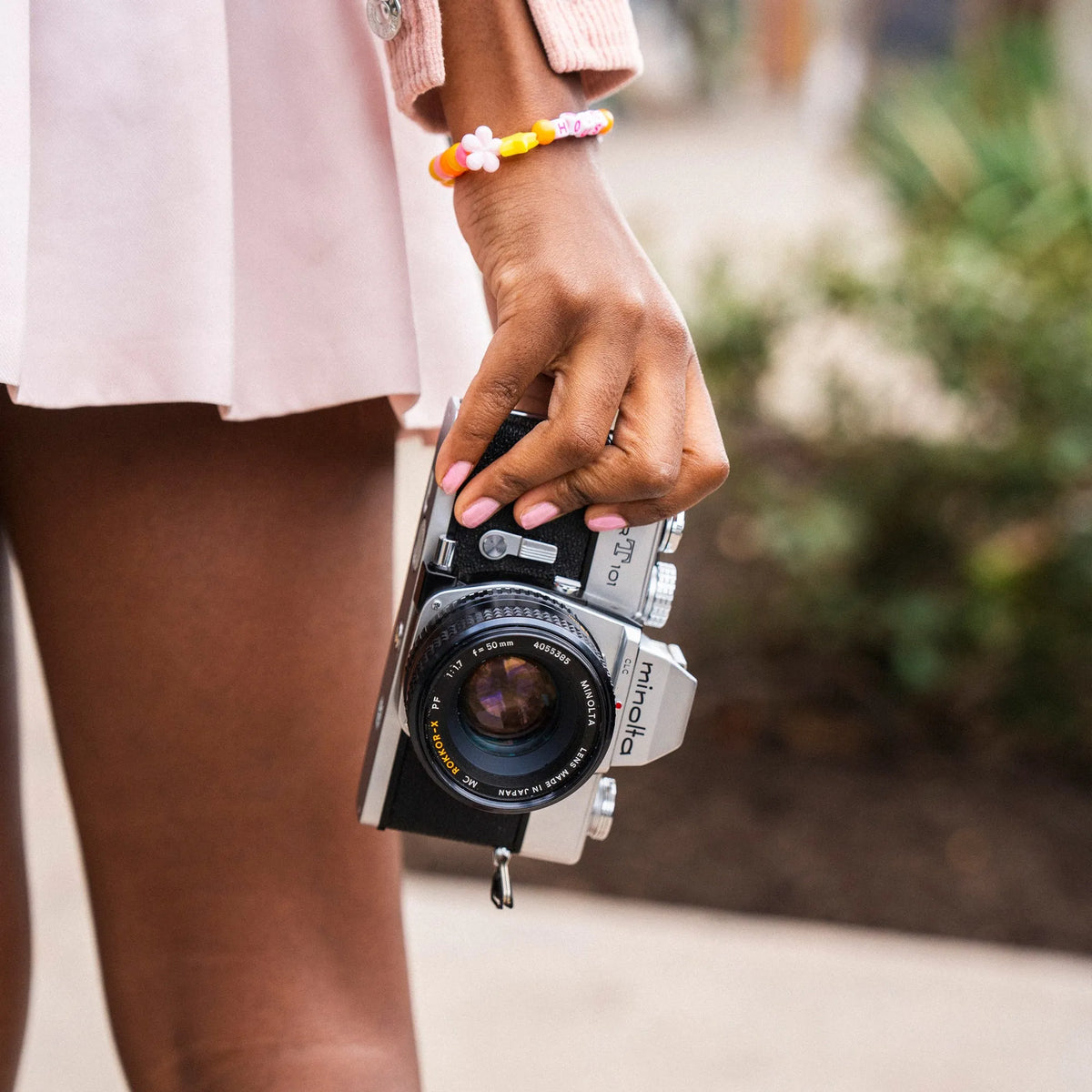 Person holding a Minolta SRT 101 35mm film camera with a blurred background