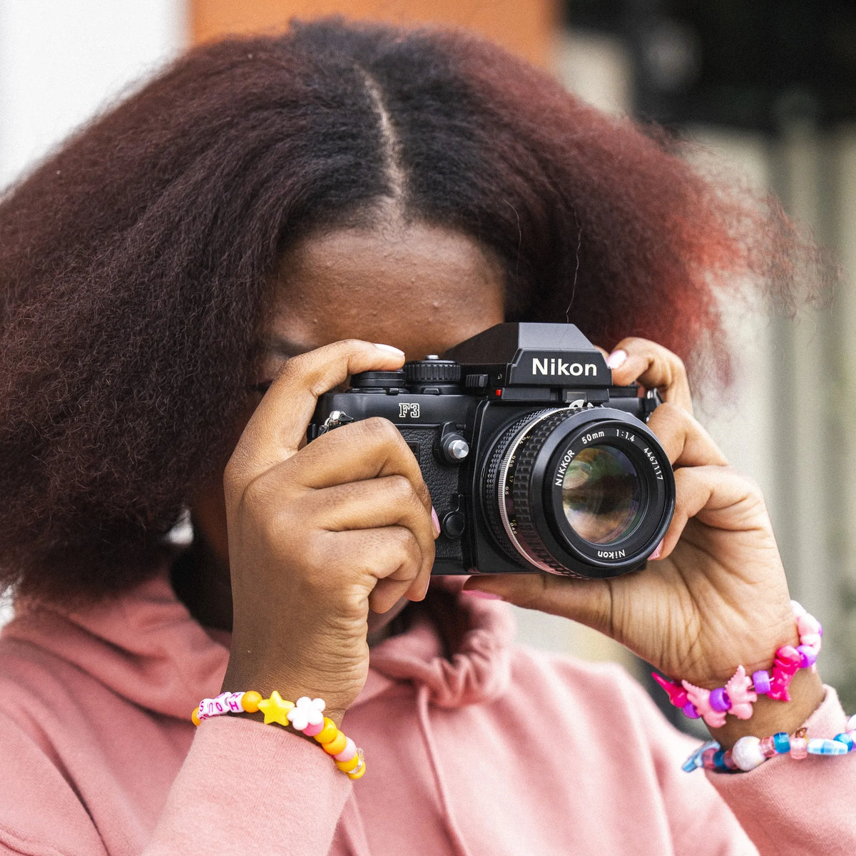 Person holding a Nikon F3 35mm Film Camera up to their face with a blurred background