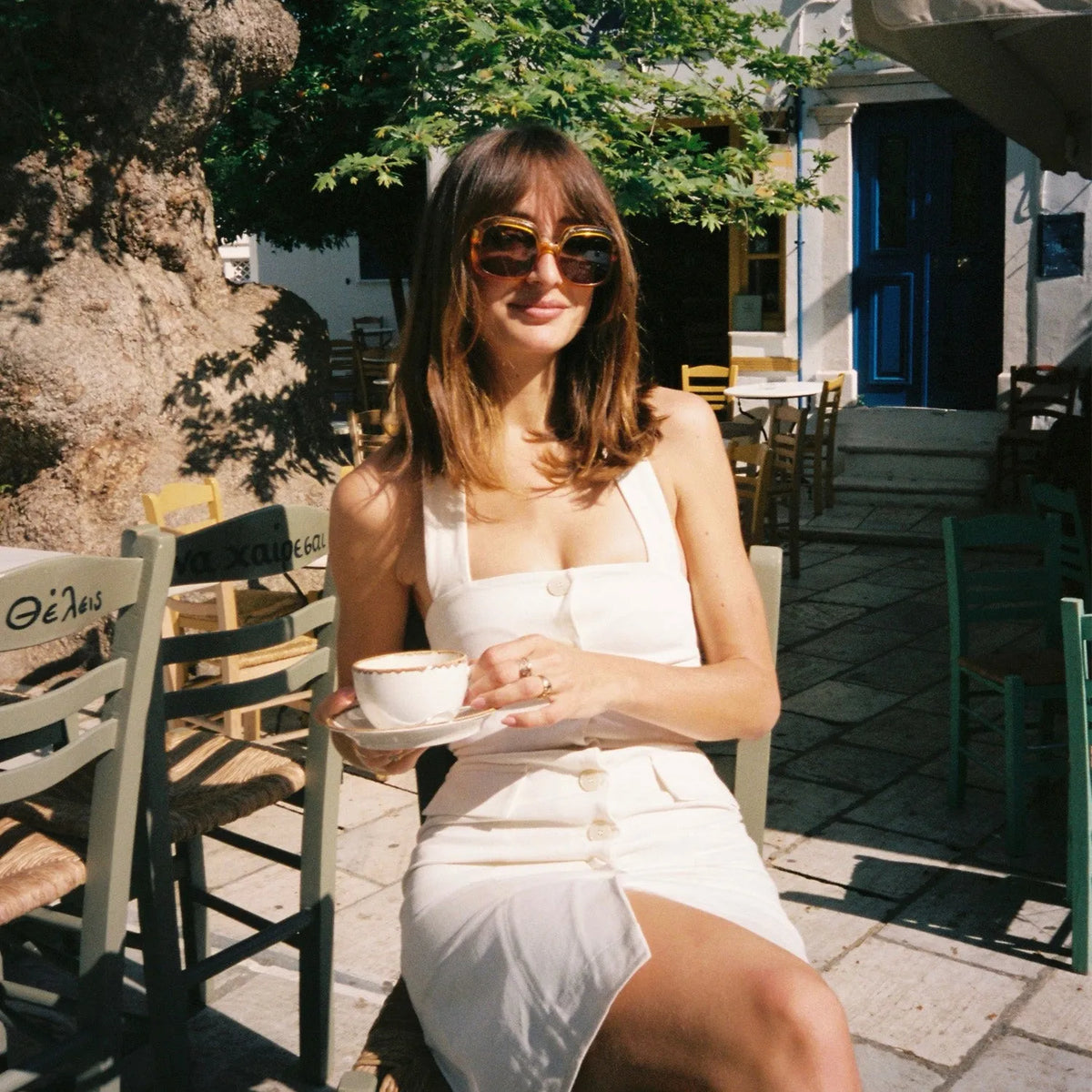 Woman in a white dress holding a cup outdoors in a sunlit area taken with the Olympus OM-10 35mm Film Camera 